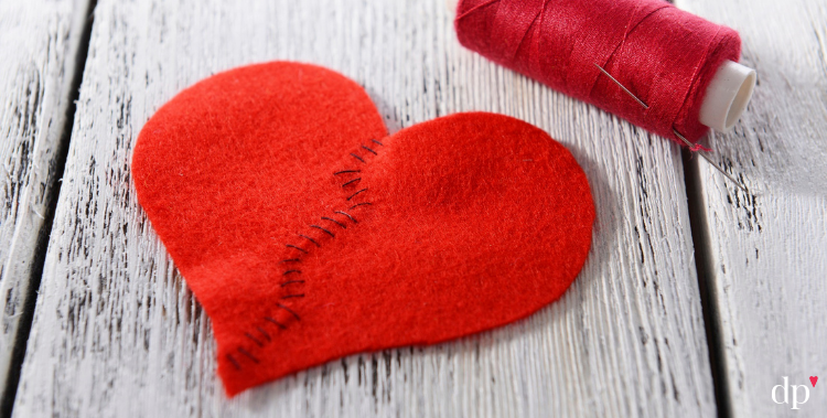 red fabric heart that's been ripped apart and stitched back up